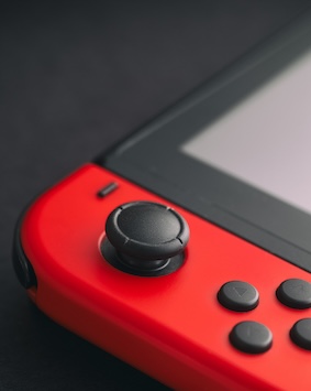 Close-up image of a red game controller joystick and buttons on a dark background.