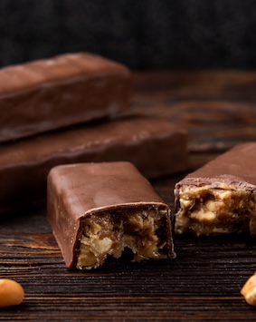 Chocolate bars with nuts on a dark wooden background, close-up.